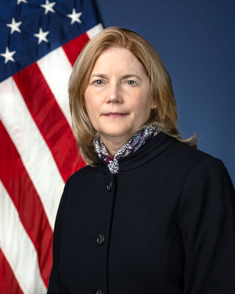 portrait photo of Suzanne Te Beau-Rodhe with U.S. flag behind her