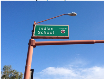 A mastarm over an intersection features a street name sign that is illuminated and has oversized letters to aid navigation.