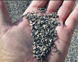 Photo shows a hand holding gravel-type rocks, calcined bauxite.