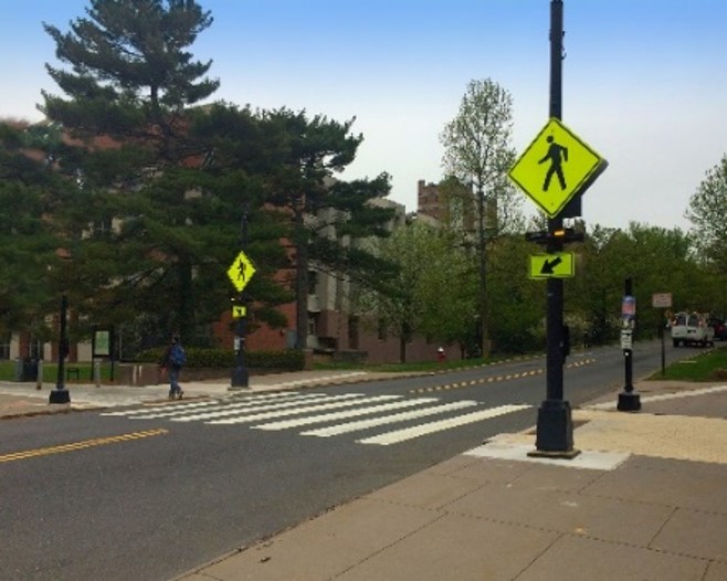 Intersection has a crosswalk and yellow pedestrian crossing signs.