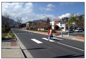 Photo of pedestrians in a crosswalk approaching a pedestrian crossing island.