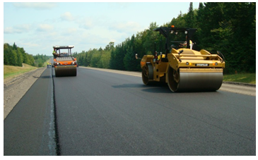 Double drum steel wheel vibratory roller machines smooth a newly paved roadway