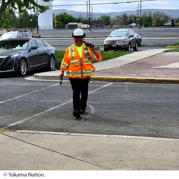 "A Yakama Nation employee, wearing a safety vest and hard hat, uses a virtual tours camera and tripod. Image Source: © Yakama Nation."