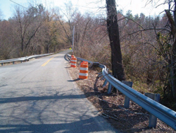 2. Photo. This photo shows drums placed next to a damaged guardrail section.