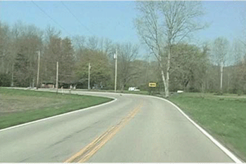 Photograph showing a curve before signage updates. A two-lane curve is present in the photo. The one-direction large arrow sign is the only sign within the curve.