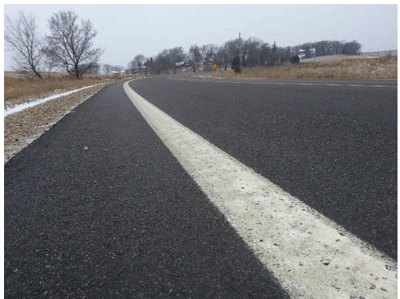 Close-up photograph of a 6-inch edge line along a curve separating the travel lane and the paved shoulder.