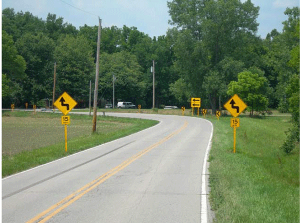 Photograph of the same horizontal curve as shown in Figure D-3 after signage updates. In addition to the existing one-direction large arrow sign, chevrons are installed on the outside of the curve.