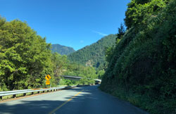 "This is a photo of a rural road going through a mountainous area with a number of curves."