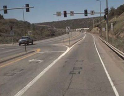 "Photograph of an intersection that was converted to a continuous green T. Photo is taken from the flat of the T on the approach to the intersection, with the stem to the left. The intersection features a dedicated lane for vehicles turning from the stem onto the flat of the T."