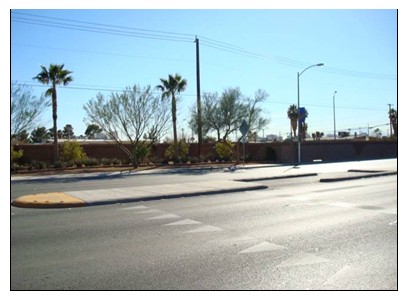 Photo of a mid-block crossing with refuge island where the offset path is fostered by a cut out pedestrian path; no bollards are present.