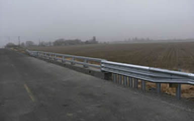 "A bridge over a culvert features safety rails."