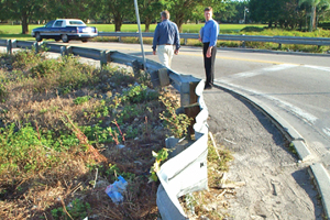 Photo showing two people from a Road Safety Audit team inspecting a damaged guide rail.