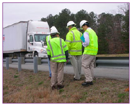 Four people conducting a safety audit near a guard rail.