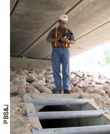 An inspector records information on an outfall located under a highway overpass. In situations such as this where the overpass blocks transmission of GPS satellite signals, inspectors can define the outfall location by clicking on a detailed aerial photograph of the site displayed in ArcPad on the tablet computer screen.