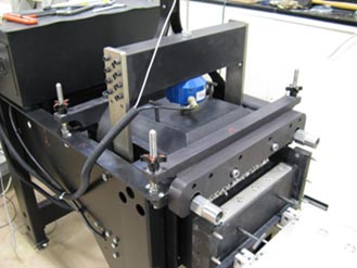 Figure 1. This is a photo that shows a large-scale direct shear device under operation. The bottom box is displacement allowing some of the aggregate being tested to show in the figure. 