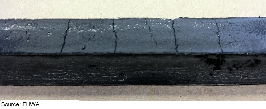 Photo of a long black beam showing very shallow vertical cracks without fractures when CNF is used. The beams did not fracture through the shallow cracks during the bending test. Photo of a long black beam showing very shallow vertical cracks without fractures when CNF is used. The beams did not fracture through the shallow cracks during the bending test.
