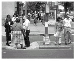 Pedestrians standing on median with city backdrop