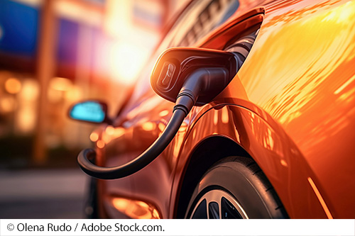 Close-up of an electric charger plugged into a vehicle. Image Source: © Olena Rudo / Adobe Stock.com.