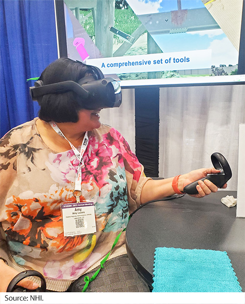 A woman sitting using the virtual goggles with a control handle in both hands. Image Source: NHI.