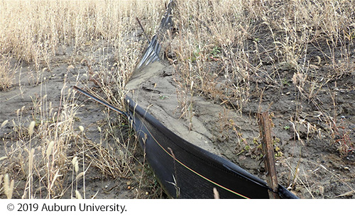 A damaged silt fence at a construction site covered with soil and debris. Image Source: © 2019 Auburn University.