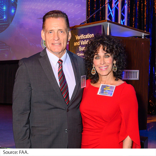 A man and woman pose in front of the stage in an auditorium. Image Source: FAA.