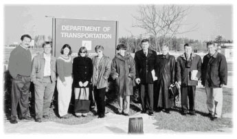 Group of Transportation officials posing in front of the DOT sign outside