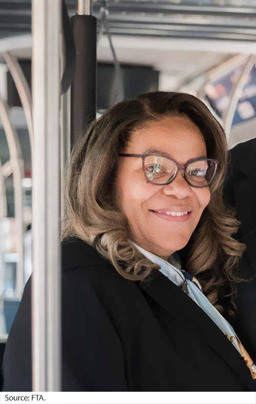 A woman smiles aboard train. Image Source: FTA.