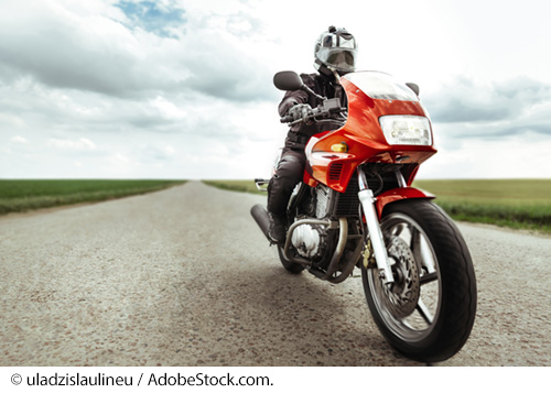 Person riding a red motorcycle on a country road. Image: © uladzislaulineu / AdobeStock.com.