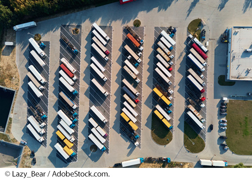 An aerial view of a parking lot with parked trucks. Image: © Lazy_Bear / AdobeStock.com.