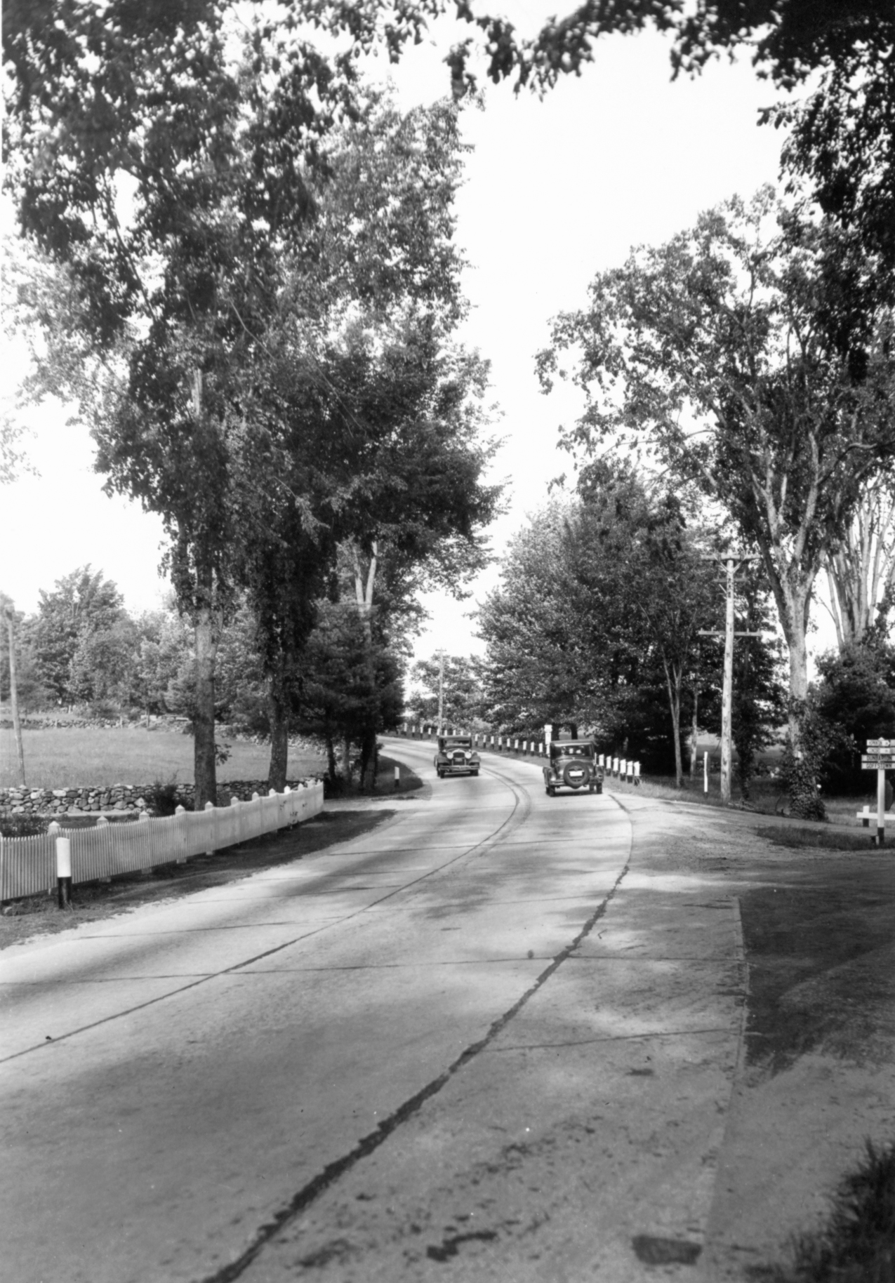 Two cars driving in opposite directions on a two-lane road.