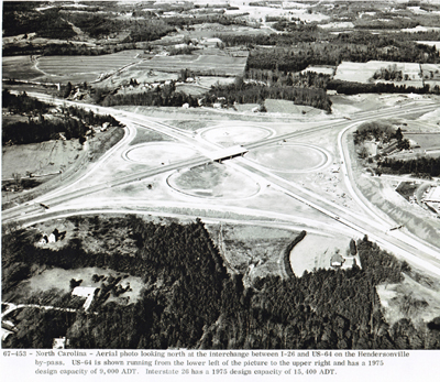 North Carolina - Aerial photo looking north at the interchange between I-26 and U.S. 64 on the Hendersonville by-pass. U.S. 64 is shown running from the lower left of the picture to the upper right and has a 1975 design capacity of 9,000 ADT. Interstate 26 has a 1975 design capacity of 15,400 ADT.