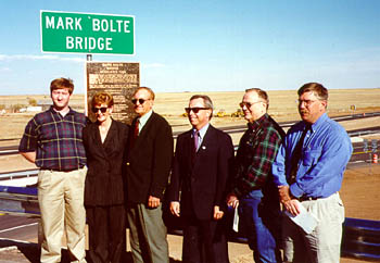 Photo of group of people standing on bridge in front of "Mark Bolte Bridge" sign